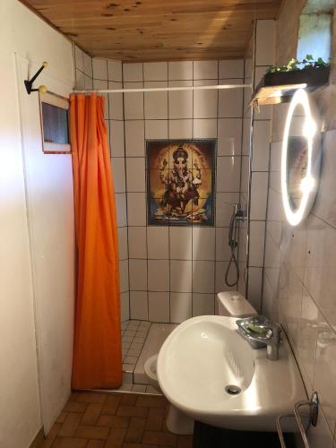 La salle de bains est pourvue d'un rideau de douche orange et d'un lavabo. dans l'établissement La petite maison O bord de l'eau, à Bernières-le-Patry
