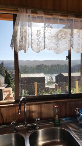 a window over a kitchen sink with a view of a building at Casa Atardecer Vichuquén in Vichuquén