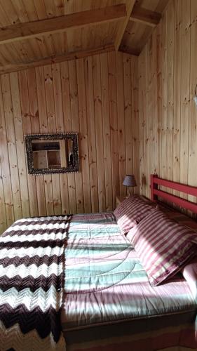 een slaapkamer met een bed in een houten hut bij Casa Atardecer Vichuquén in Vichuquén