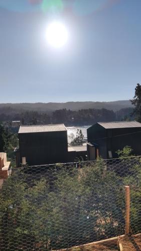 two buildings in a field with a body of water at Casa Atardecer Vichuquén in Vichuquén