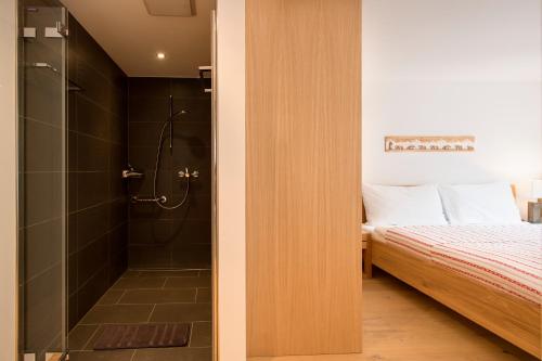 a bathroom with a shower next to a bed at Casa delle Stelle by Zermatt Premium Apartments in Zermatt