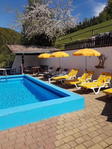 a swimming pool with yellow chairs and umbrellas at Backer-Ferdl Panzio in Hinterstoder