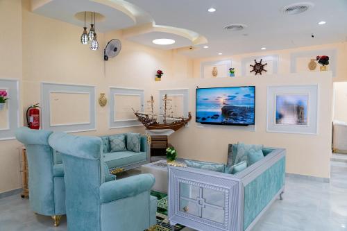 a living room with two blue chairs and a tv at Arkan Al Barzah Hotel Apartment in Sur