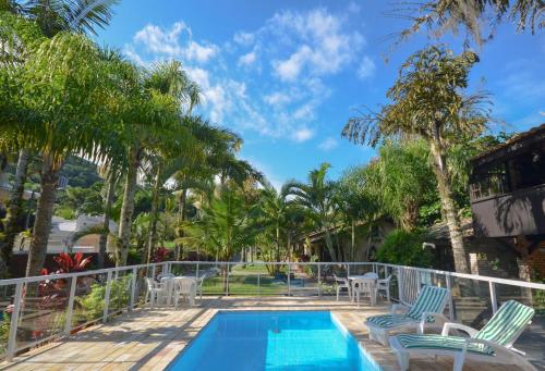 a balcony with a swimming pool and palm trees at Chalés do Holandês Eco Pousada in Bombinhas