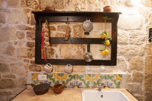 a kitchen with a sink and a stone wall at Si-Moutique, le Case-grotte degli Avi 2 in Modica