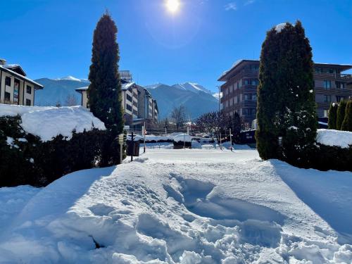 a pile of snow on a street with buildings and trees at Pirin Dream View Apartments in Razlog