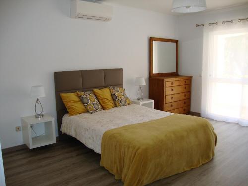 a bedroom with a large bed with yellow pillows at Belinha Guest House in Luz