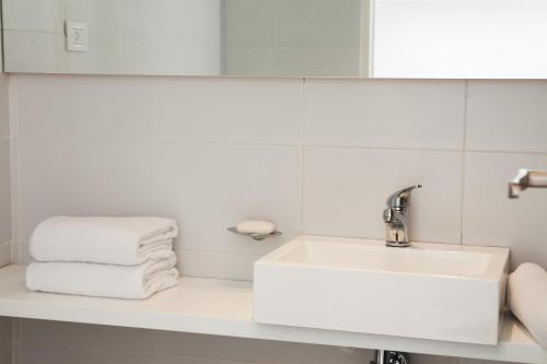 Un baño con lavabo, espejo y toallas. en Babel Studios, en Buenos Aires