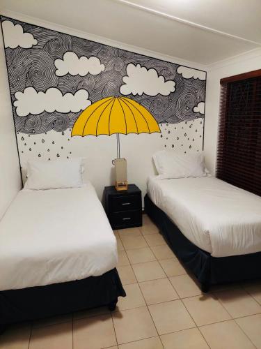 a room with two beds and a yellow umbrella at Beautiful Villa - Scottburgh, Durban in Scottburgh