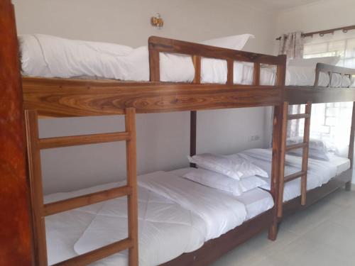two bunk beds in a room with white sheets at Mkomazi Hotels and Camps in Hegoma