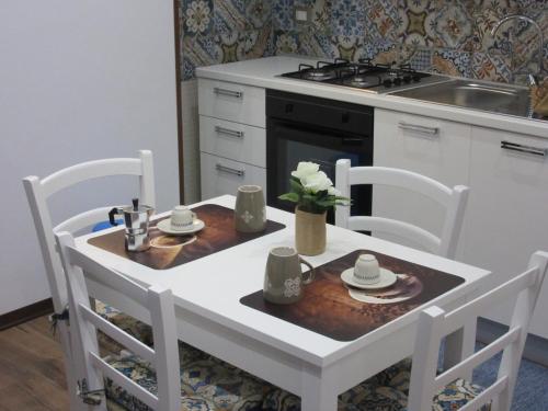 een keuken met een witte tafel en stoelen en een tafel en stoelen bij La Maiolica Blu in Trapani
