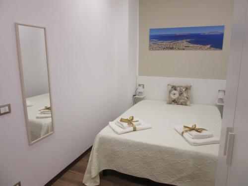 a white bedroom with a bed with towels on it at La Maiolica Blu in Trapani