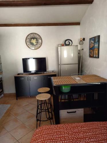 La cuisine est équipée d'un réfrigérateur, d'une table et d'un tabouret. dans l'établissement Studio climatisé dans villa calme à 15km de Cannes, à Peymeinade