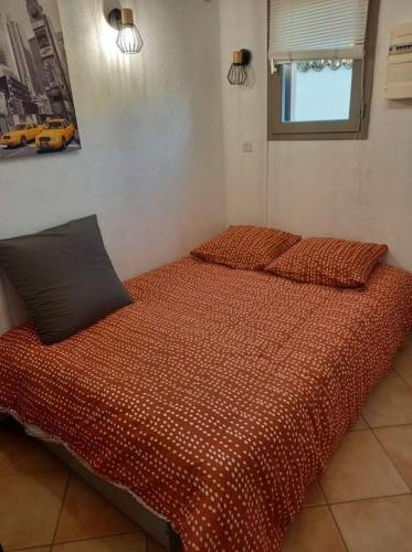 une chambre avec un lit avec une couette rouge dans l'établissement Studio climatisé dans villa calme à 15km de Cannes, à Peymeinade
