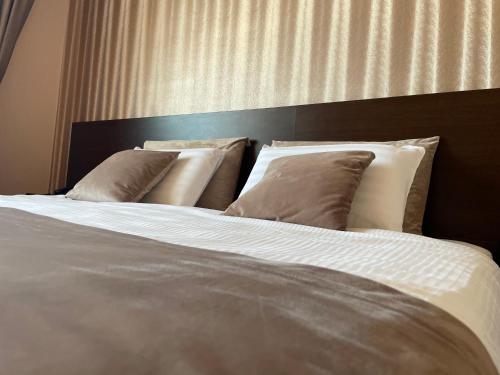 a large bed with four pillows on top of it at Hotel Athos in Bucharest
