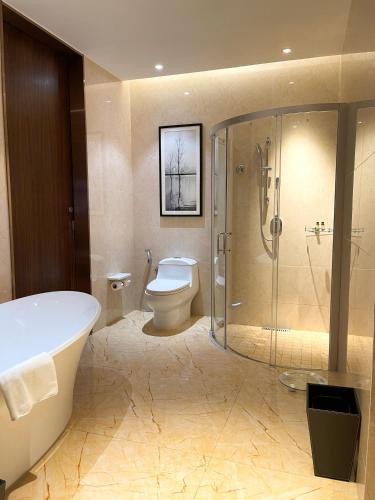 a bathroom with a tub and a toilet and a shower at Forest City Golf Hotel in Nusajaya