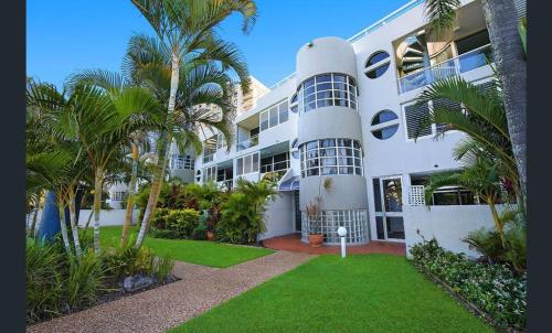 a large white building with palm trees in front of it at Sundeck Gardens in Maroochydore