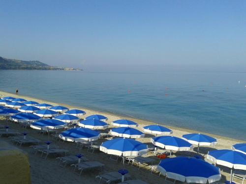 a group of blue and white umbrellas on a beach at Appartamenti Comfort in Mandaradoni