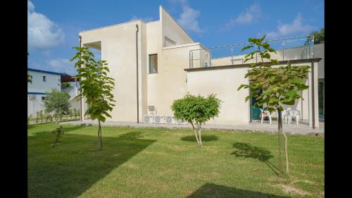 a white house with trees in the yard at Appartamenti Comfort in Mandaradoni