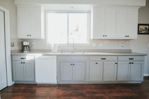 a white kitchen with a sink and a window at Central Coziness - Steps from Chico's Hub in Chico