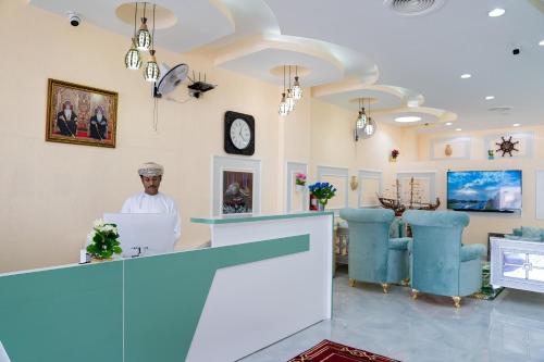 a man standing at a salon counter with a laptop at Arkan Al Barzah Hotel Apartment in Sur