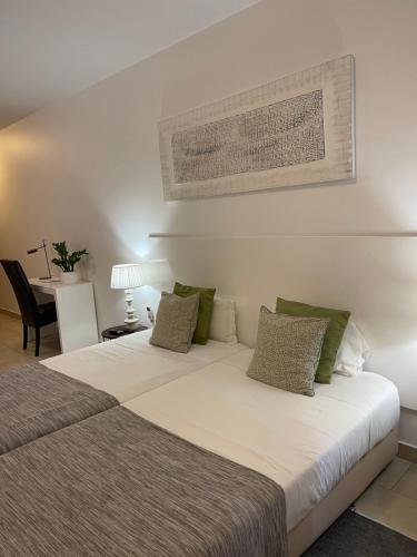 a bedroom with a large white bed with green pillows at Esmeralda Holidays Apartments in Funchal