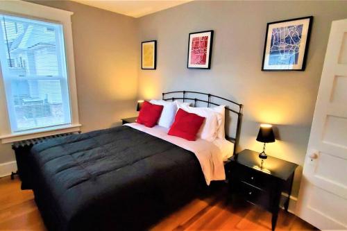 Un dormitorio con una gran cama negra con almohadas rojas en Welcome to Hat City Danbury, A Suburban Retreat en Danbury