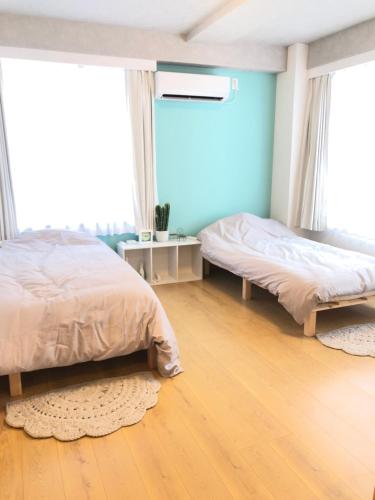 two beds in a bedroom with wooden floors and windows at Upper Hotel Ishihara in Tokyo