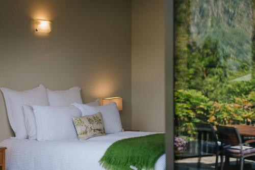 a bedroom with a white bed with a green blanket at Rimu Lodge in Hokitika
