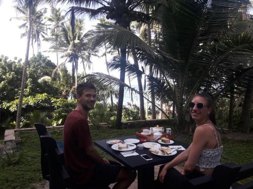 a man and a woman sitting at a table with food at SunRay Rest - Beach View Homestay in Mirissa