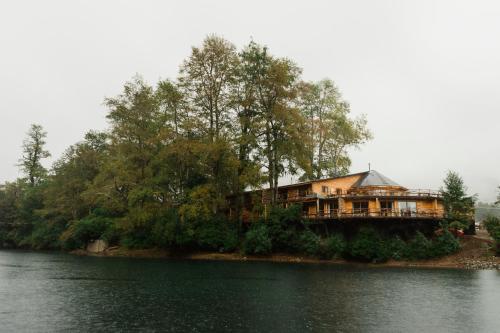 a house on an island in the middle of a lake at Huilo Huilo Apartamentos Club Huillín in Huilo Huilo
