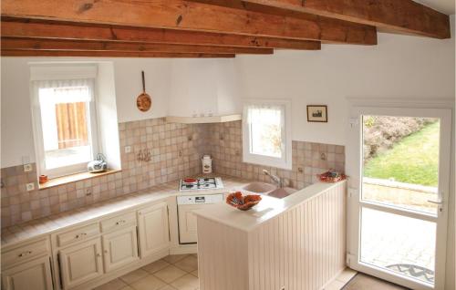 La cuisine est équipée de placards blancs, d'un évier et de fenêtres. dans l'établissement 3 Bedroom Awesome Home In Lzardrieux, à Lézardrieux