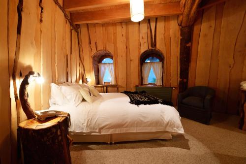 a bedroom with a bed and a chair and windows at Huilo Huilo Montaña Mágica in Huilo Huilo