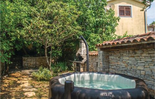 een hot tub in een tuin met een stenen muur bij Lovely Home In Nedescina With Sauna in Nedeščina