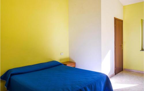 um quarto com uma cama azul e uma parede amarela em Lovely Home In Zambrone With Kitchen em Zaccanopoli