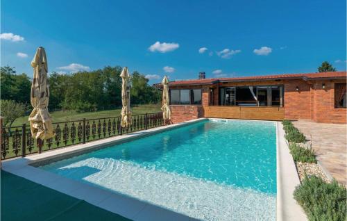 a swimming pool with umbrellas in front of a house at Gorgeous Home In Repusnica With Sauna in Repušnica