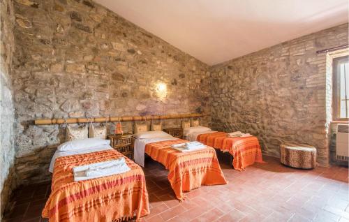 a room with three beds and a stone wall at Materno 4 in Radicondoli