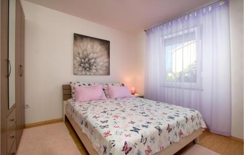 een slaapkamer met een bed met roze kussens en een raam bij Pet Friendly Home In Peroj With Kitchen in Peroj