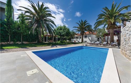 una piscina nel cortile di una casa con palme di Amazing Home In Zdrelac With Wifi a Ždrelac