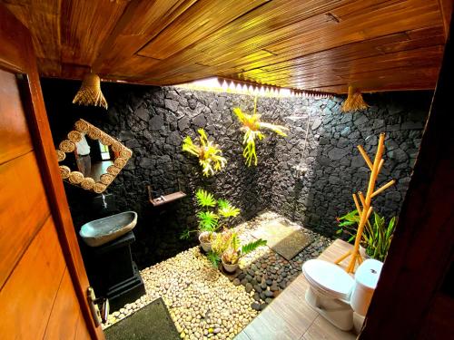 a bathroom with a toilet and a stone wall at Pinggan caldera in Baturaja