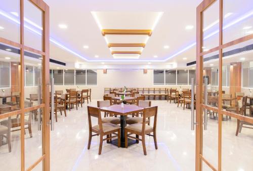 a dining room with tables and chairs and windows at Sunstar Residency & Food Plaza Pala in Lālam