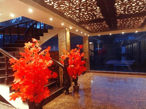 a lobby with red flowers in vases and stairs at HYDERS PARK- THE LUXURY HOTEL in Kodaikānāl