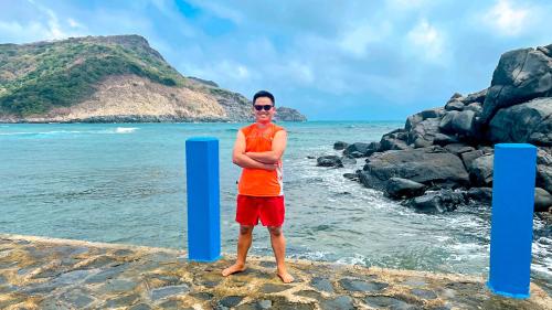 a man standing on the beach next to the ocean at Eden House & Coffee Con Dao in Con Dao
