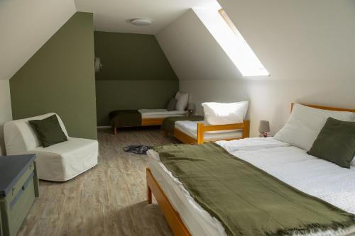 a bedroom with a bed and a couch and a chair at Mézes Vendégház és Apiterápiás központ in Vizsoly