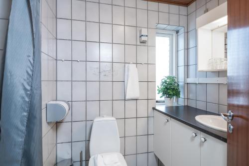 a white tiled bathroom with a toilet and a sink at Hotel Frederikshavn in Frederikshavn