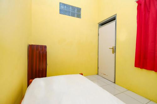 a bedroom with a bed and a door with a red curtain at OYO Life 2867 Kos Kuning in Solo