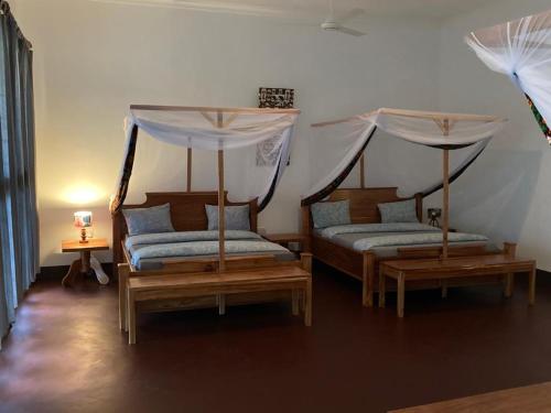 a bedroom with two beds with mosquito nets at Camp Bastian Mikumi in Mikumi
