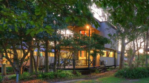 a large white house with trees in front of it at Wooli River Lodges in Wooli