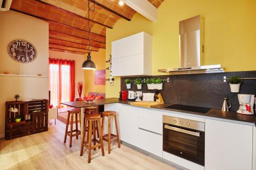 a kitchen with yellow walls and white cabinets and bar stools at Lovely & bright Bogatell beach apartment in Barcelona