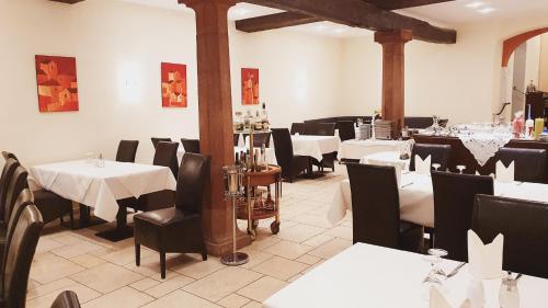 Hotel Rebmann في لينسفياير: مطعم بطاولات بيضاء وكراسي سوداء وطاولات وكراسي بيضاء